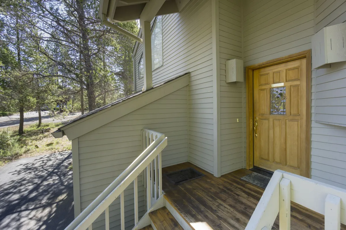This image captures the welcoming front porch of White Elm 29, with inviting wooden steps, a sturdy front door, and lush trees surrounding the property. The porch and adjacent greenery suggest easy access to the outdoors and ample space for pets to explore before and after neighborhood adventures.