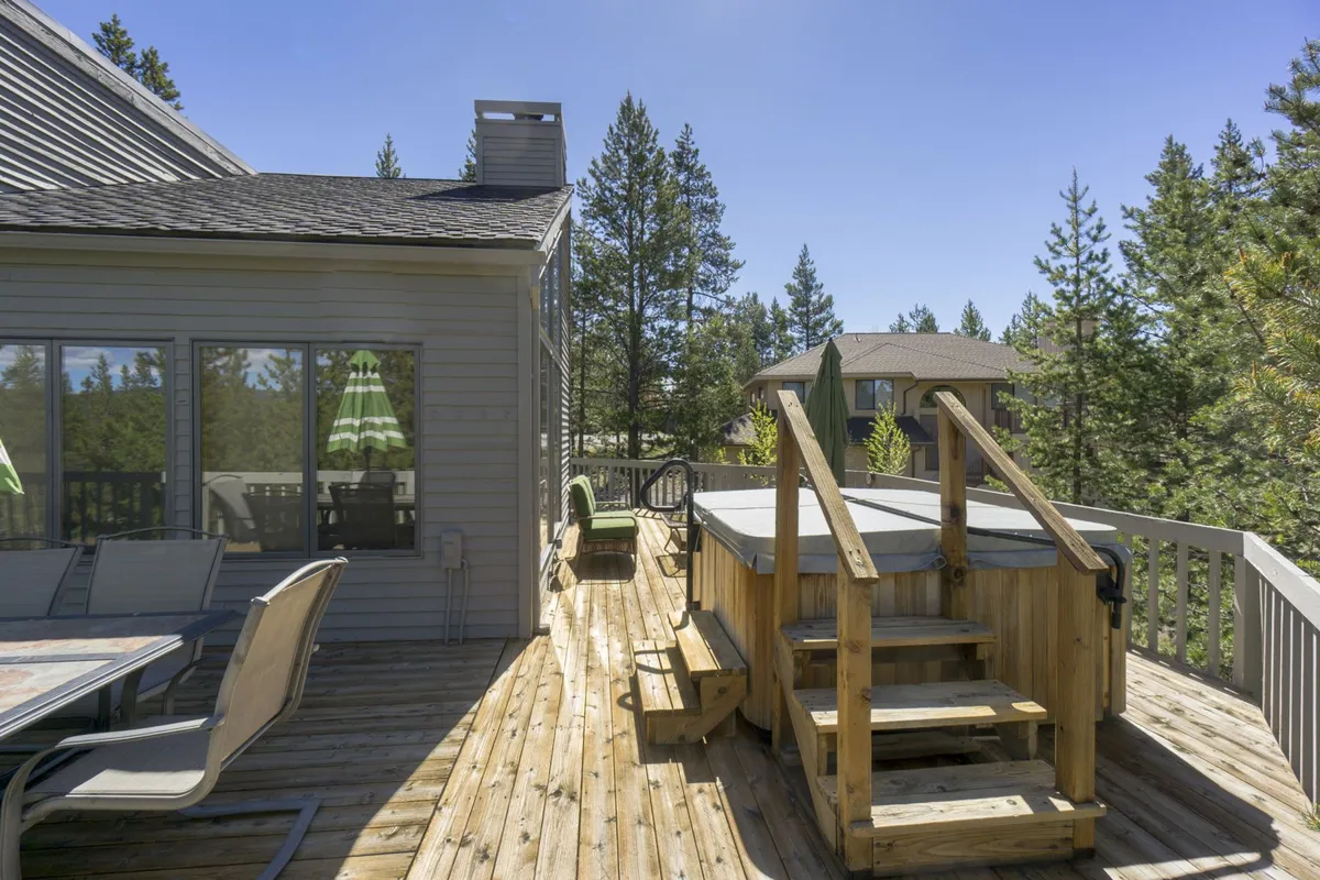 An inviting exterior view of a private hot tub set on a wooden deck, surrounded by tall trees. The tranquil setting suggests relaxation and a connection to nature, perfect for unwinding after a day of exploration.