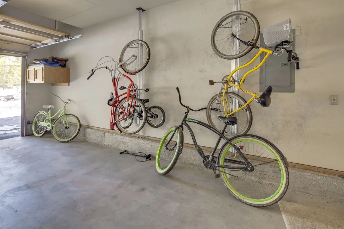 A bright, organized garage showcasing a colorful row of eight bicycles lined up next to a practical storage unit. The clean space is ready for guests to store their bikes or car, setting the scene for active adventures right from the home base.