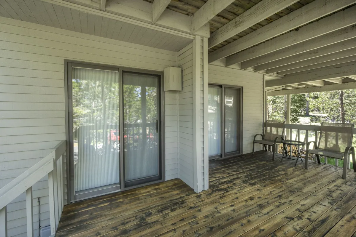 This image shows a tranquil wooden deck attached to the home, accessed through sliding glass doors. Outdoor seating is arranged to face the surrounding natural landscape, evoking an inviting space for relaxation, reading, or simply enjoying the fresh air. The deck visually connects interior living spaces with the outdoors, emphasizing year-round enjoyment of Sunriver’s natural environment.