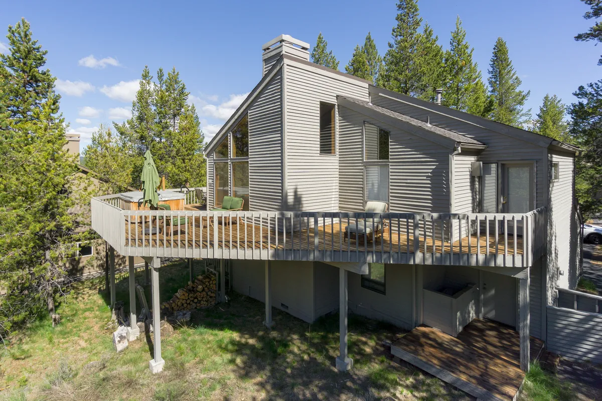 A peaceful deck area with green chairs set against a backdrop of towering trees and the home’s exterior. The scene suggests a seamless indoor-outdoor living experience, ideal for morning coffee or stargazing after an active day.